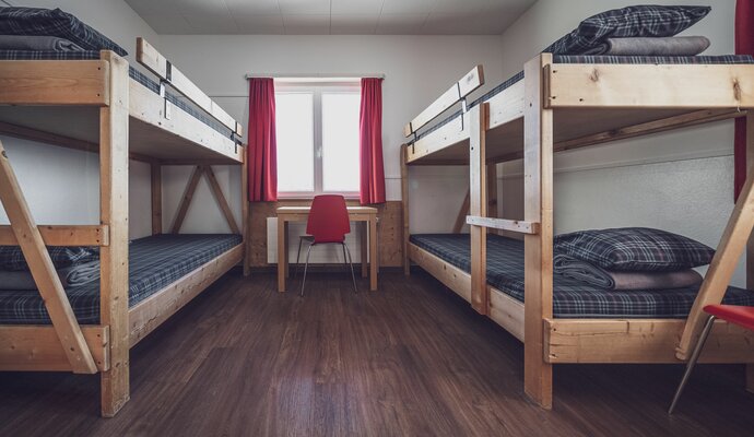 Multi-bed room with window and table | © Davos Klosters Mountains