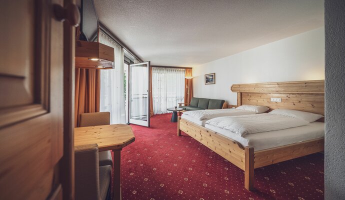 Large room with double bed, balcony and red carpet  | © Davos Klosters Mountains 