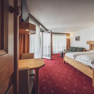Large room with double bed, balcony and red carpet  | © Davos Klosters Mountains 