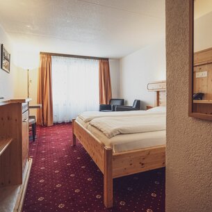 Room with double bed, large windows and curtains  | © Davos Klosters Mountains 