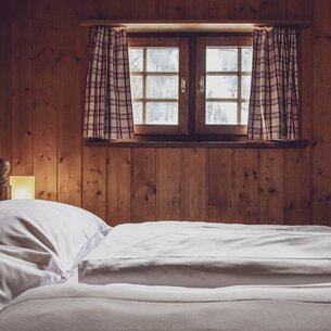 Doppelbett mit kleine Fenster | © Davos Klosters Mountains