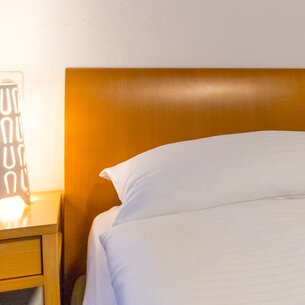 Hotel bed with bedside table | © Davos Klosters Mountains