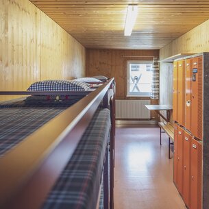 Room with multiple double bunk beds and lockers | © Davos Klosters Mountains 